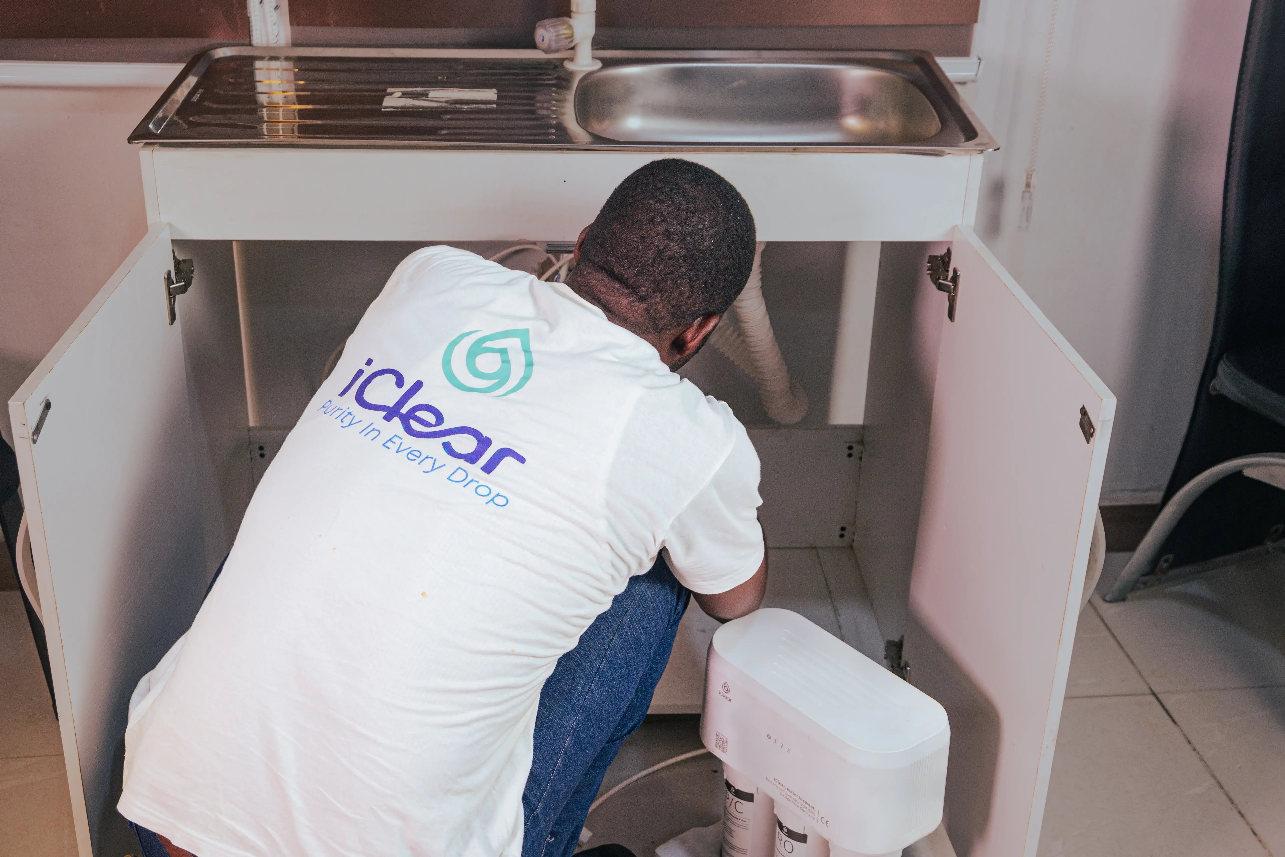 Image of a man installing clean water technology under a kitchen sink