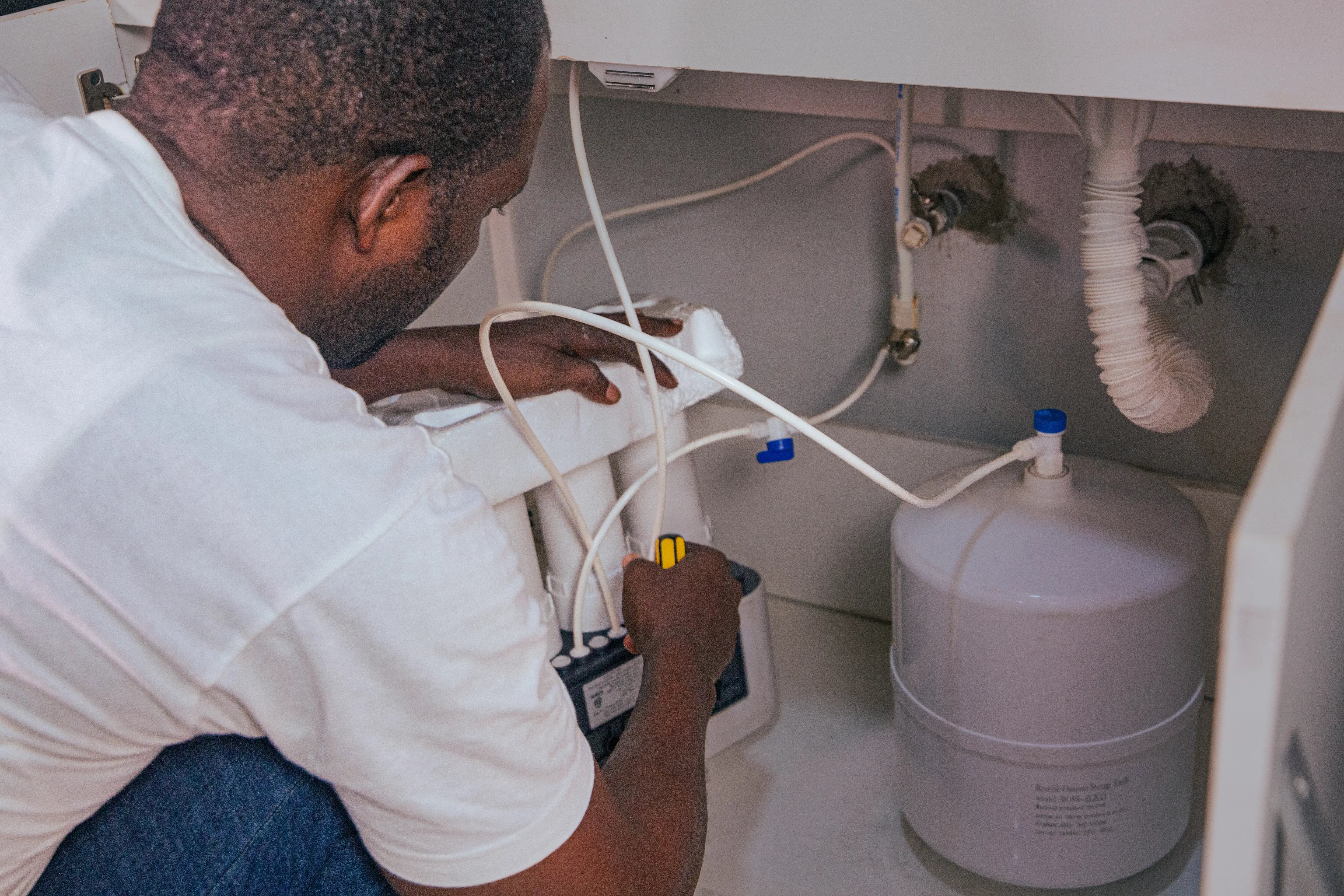 Picture of a plumber fixing a water purifier for a client